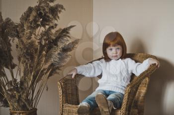 Portrait of a little girl in the white sweater.