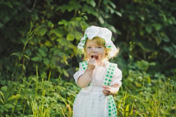 Little girl in green and white dress walking in the garden.