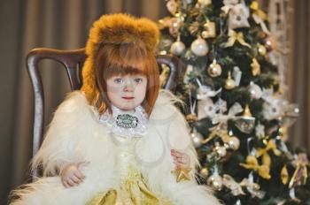 Portrait of a child in a fur coat around the Christmas tree.