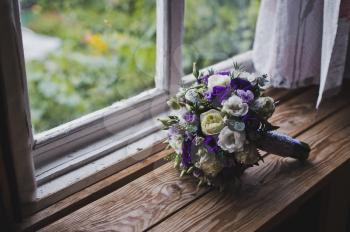 A bouquet of flowers lying on a wooden window sill.