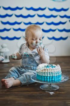 Little boy eats with his hands on the cake.