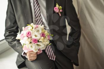 Bouquet of beautiful flowers in hands of the groom.