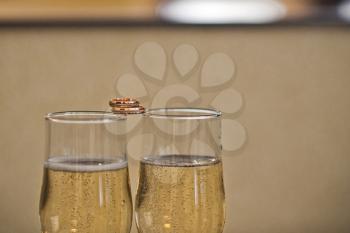 Glasses with champagne and rings on a table.