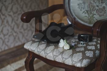Belt boutonniere and shoes are on the chair.