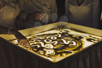 The process of drawing a picture of the sand on the illuminated glass.