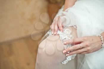 The bride dresses an ornament on a foot.