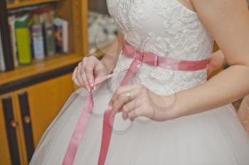 The girlfriend of the bride helps to dress a wedding dress.