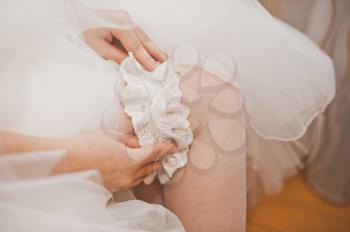 The young woman dresses an ornament on a foot before wedding.
