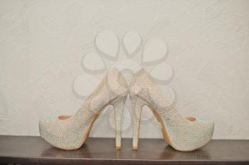 White wedding shoes stand on a table.