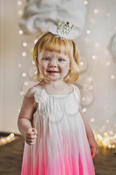 Happy child in a soft dress on the background of lights.