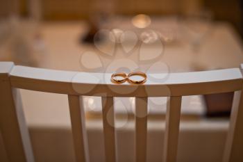 Two gold rings lie on a chair back.