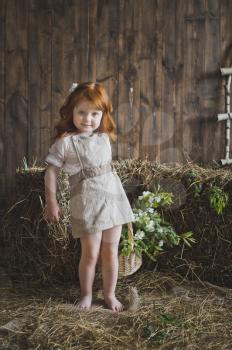 Small girl standing among the hay in the Studio.