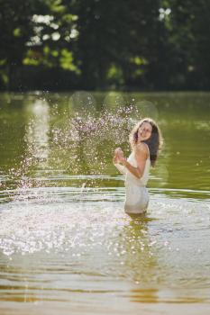 Portrait of a girl in a short white dress standing waist-deep in water.