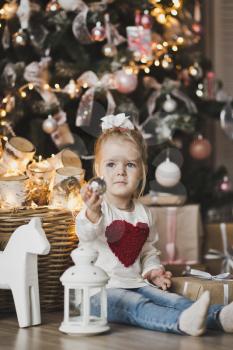 Portrait of a child sitting on the floor near the Christmas tree.