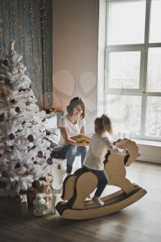 Mother and daughter sitting near the Christmas tree.