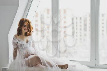 Close-up portrait of girl in a negligee on background of the window.