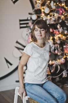 Portrait of a beautiful girl in a white t-shirt on the Christmas tree.