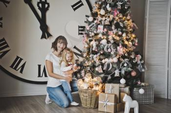 Mother and her daughter on background of great white watches and Christmas trees.