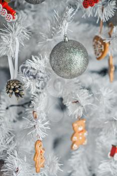Silver Christmas tree decorated with balls and figurines.