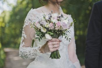 The bride holds a bouquet of flowers in a fragile handle.