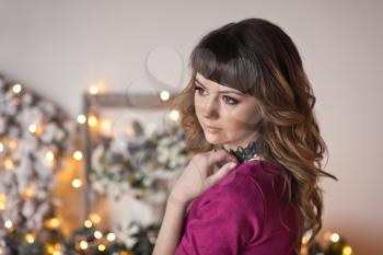 Close-up portrait of girl in red dress on the background of Christmas decorations.