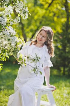 The girl in the position dressed in white resting in a beautiful garden.