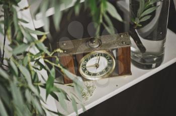 Antique clock on a shelf near vases with branches of a Bush.
