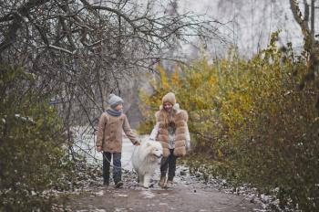 Girl and boy on a walk with the dog breed Samoyed.