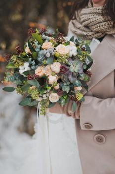 Original bouquet of flowers in the hands of women against the winter landscape.