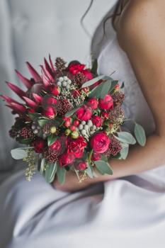 Red bouquet of flowers in hands of the girl in the white dress.