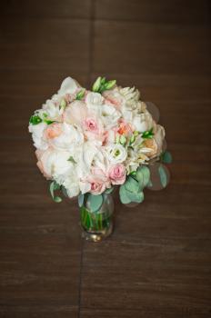 A beautiful bouquet of roses in a vase on the varnished floor.
