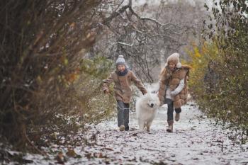 Boy and girl running a race with the Samoyed.