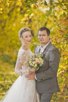Portrait of a beautiful married couple on the autumn background bright forest.