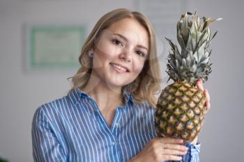 Girl shows off a pineapple.