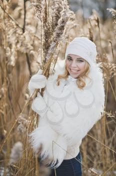 Beautiful blonde girl stands in winter, in thickets of reeds.