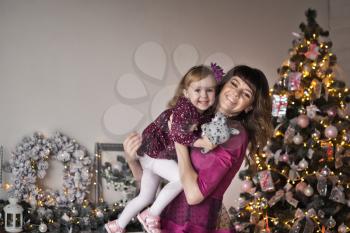 The girl and her mother in a crimson dress Studio background Christmas decorations.