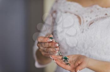 Earrings with green stones in the womens hands.