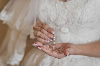 The bride shows the earrings holding them in the palms.