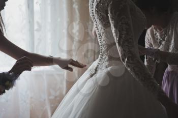 Hand fasten buttons on a wedding dress.