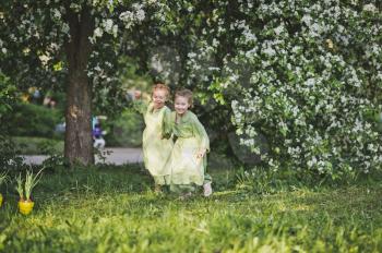 Girls running around the garden holding hands.