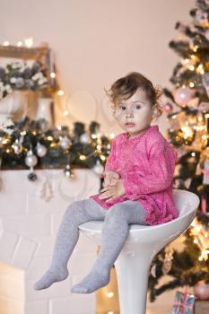 Portrait of a child on a background of Christmas lights garlands on the tree.