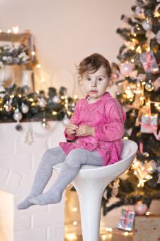 Portrait of a child on a background of Christmas lights garlands on the tree.