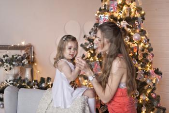 Mother and daughter on the background of sparkling Christmas garlands.