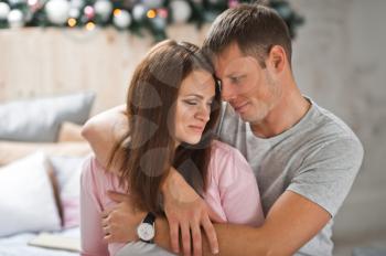 Newlyweds gently hugging on the background of the Christmas tree.