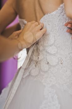 The girlfriend helps to wear a wedding dress.