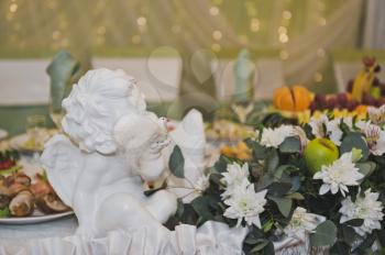 White angel amongst the flowers on the holiday table.