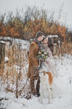 Winter portrait of newlyweds in the woods with a dog on a leash.