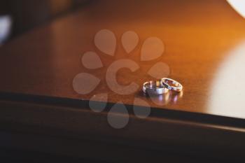 Wedding rings on the varnished table near the lamp.
