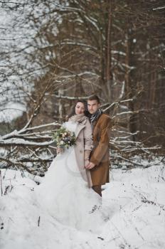 Beautiful portrait of bride and groom on winter forest background.