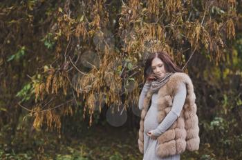 The girl in the last months of pregnancy among the fading autumn trees.